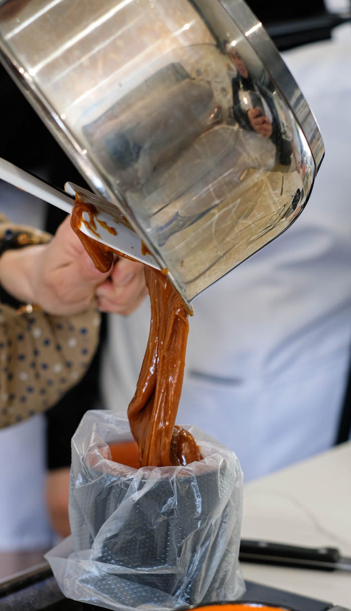 A chef pours freshly made caramel into a mold during dessert preparation in a professional kitchen.