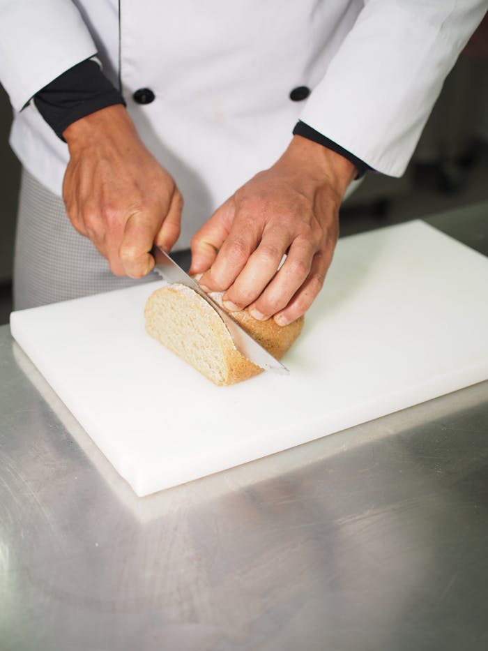 Chef slicing fresh bread on a cutting board with precision and care.