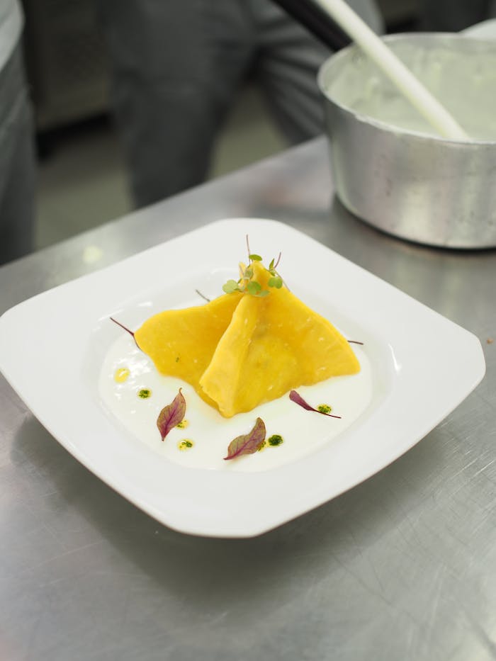 Delicious gourmet ravioli served with cream sauce, captured in a professional kitchen setting.